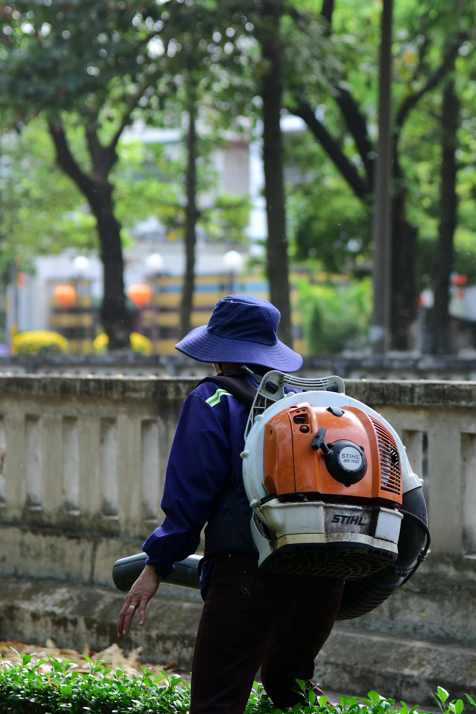 Backpack-blower clearing late-fall leaves into a tidy pile on a residential lawn.